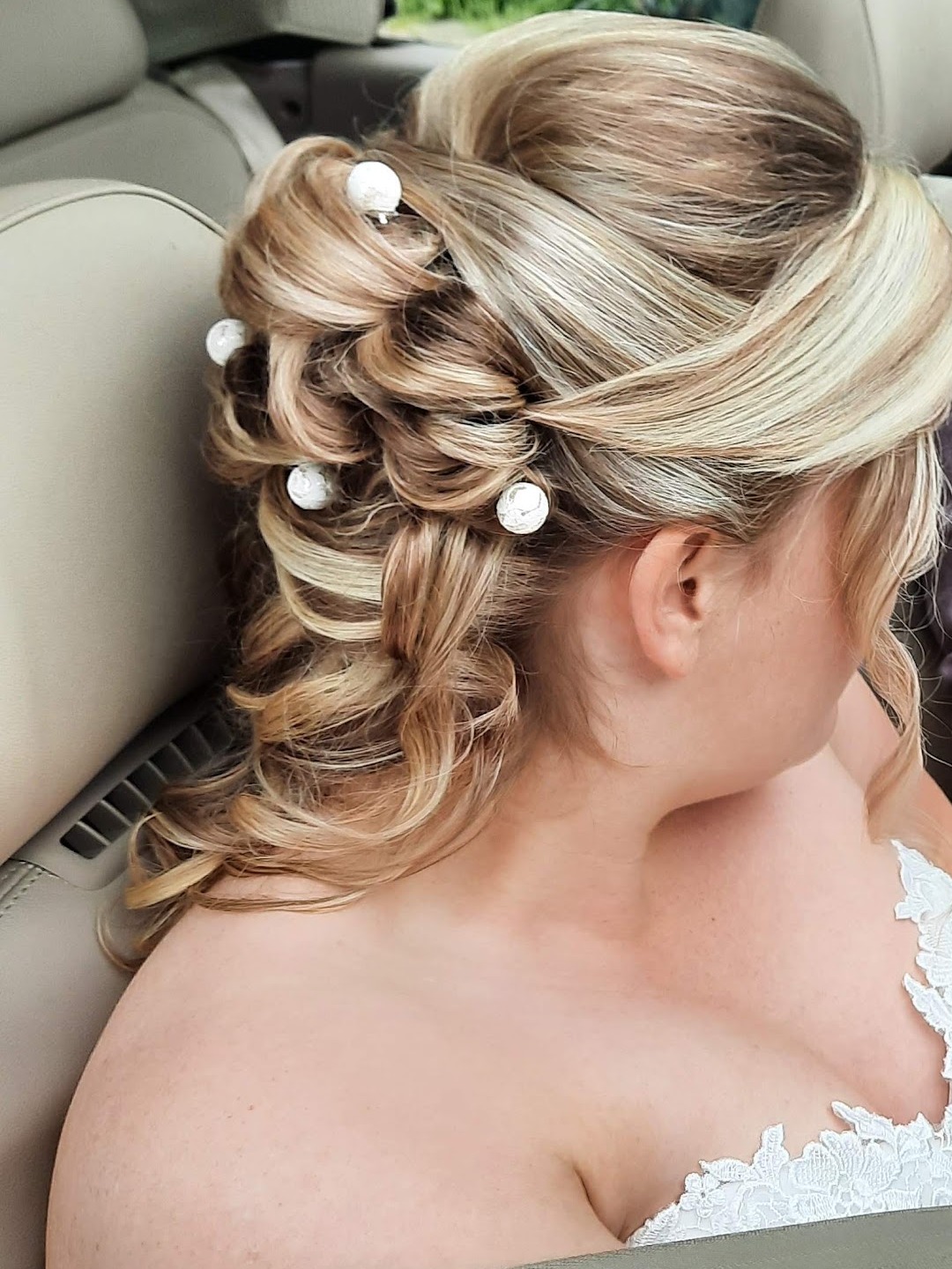 Blond bruidskapsel met opgestoken krullen en witte haaraccessoires